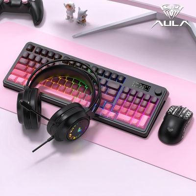 Gaming keyboard, headphones, and mouse on a pink surface with AULA branding.